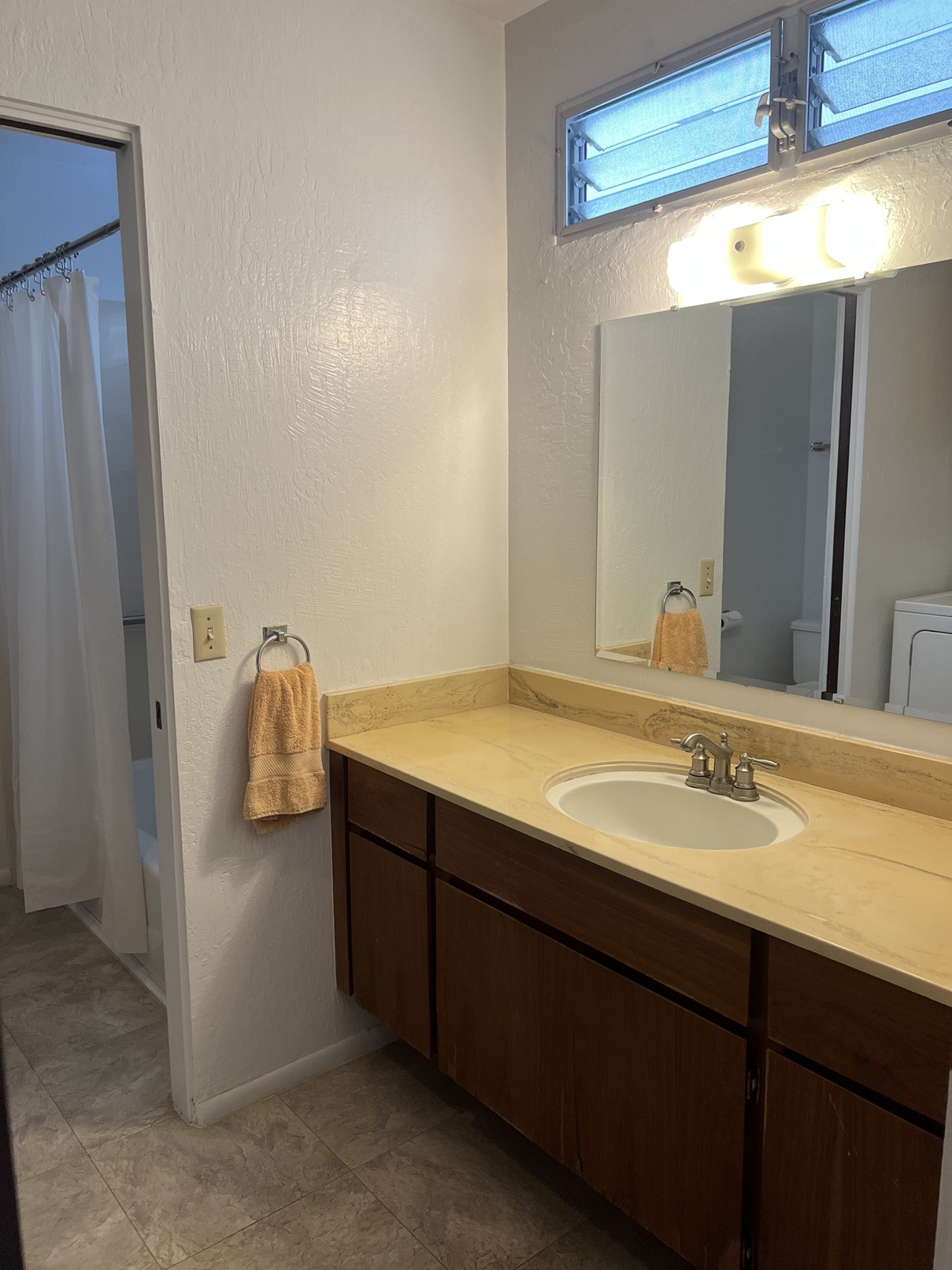 A bathroom with a sink, mirror, and a towel hanging on the wall.